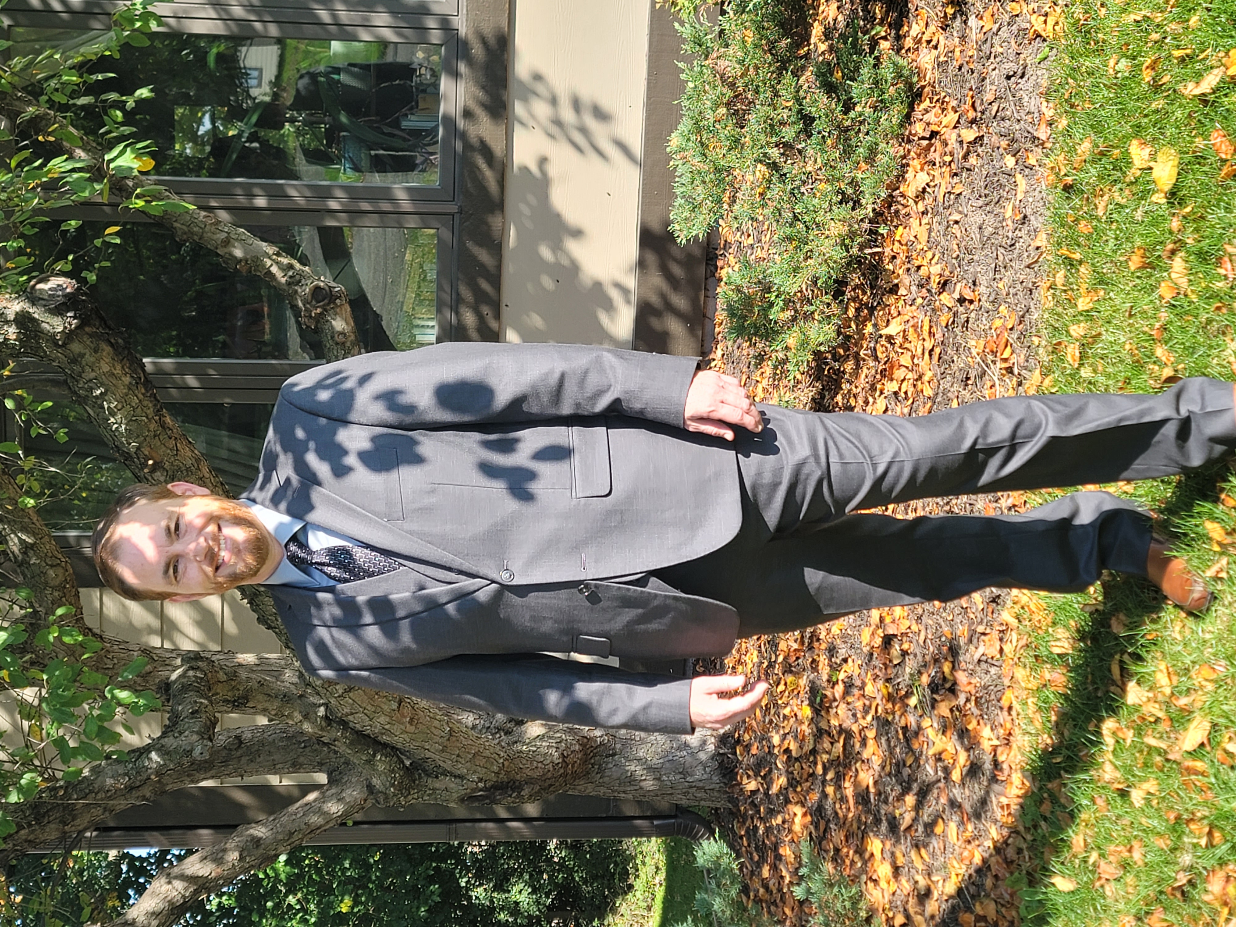Paul Gover standing outdoors in a gray suit beneath a leafy tree