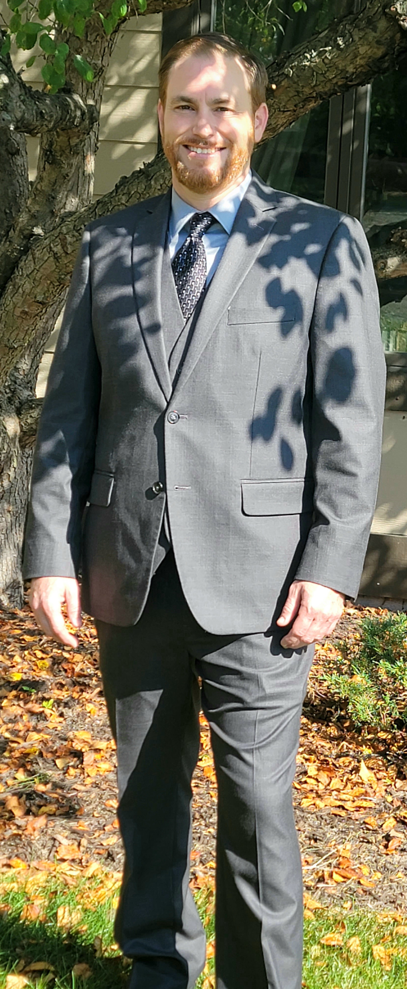 Paul Gover standing on a lawn in a gray suit beside a house