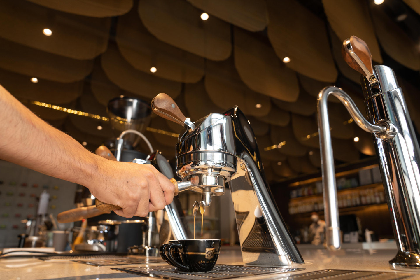 Hands preparing espresso with a commercial coffee machine