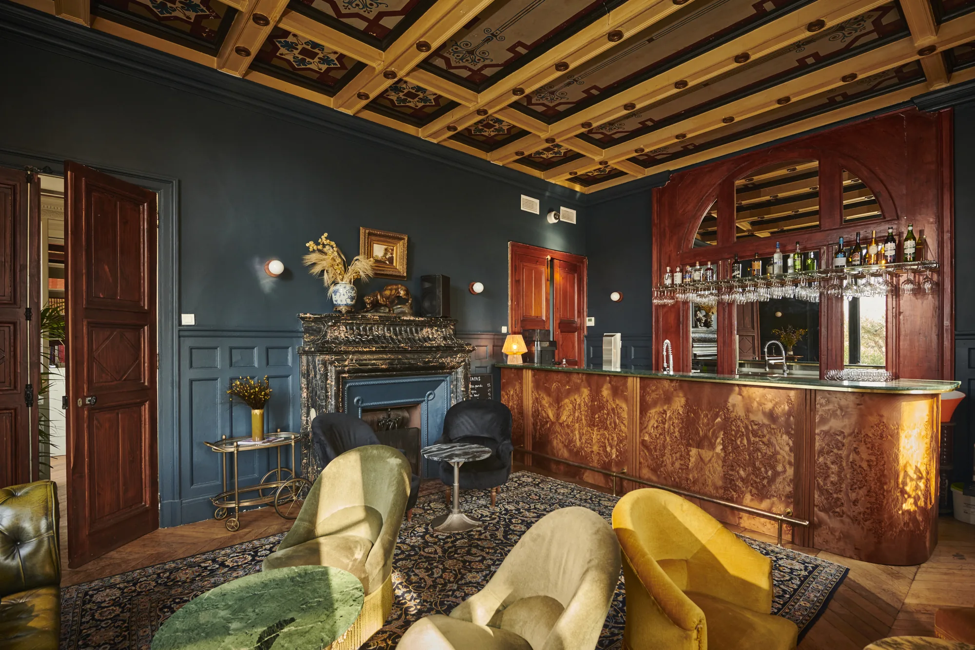 Le Bar 1874 : comptoir de loupe d'orme, murs bleu nuit, fauteuils de velours et plafond à caissons peints
