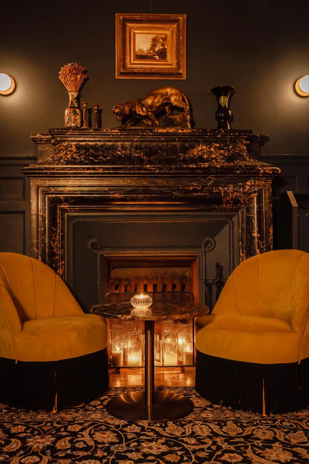 Deux coupes levées devant la cheminée du bar, seau à champagne à la lumière des bougies