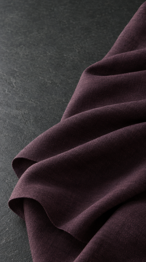 A length of aubergine woven fabric opening into broad, soft folds.