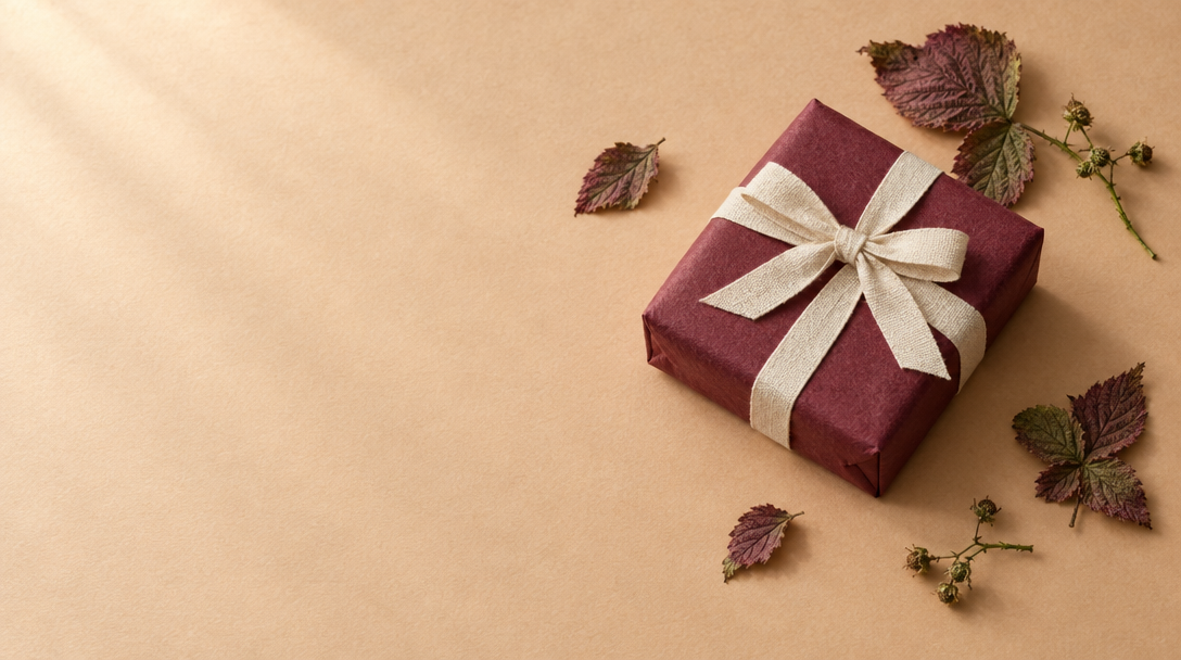A small parcel wrapped in berry-colored paper with a cream ribbon.